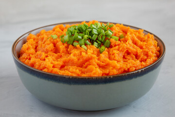 Homemade Creamy Mashed Sweet Potatoes with MIlk and Butter in a Bowl on a gray background, side view. Close-up.