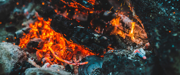Vivid smoldered firewoods burned in fire closeup. Atmospheric background with orange flame of...