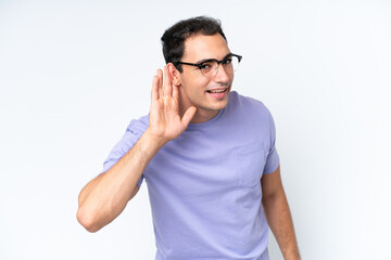 Young caucasian man isolated on white background listening to something by putting hand on the ear