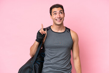 Young sport caucasian man with sport bag isolated on pink background intending to realizes the...