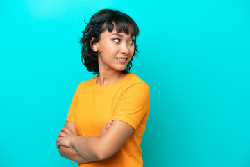 Young Argentinian woman isolated on blue background looking to the side and smiling