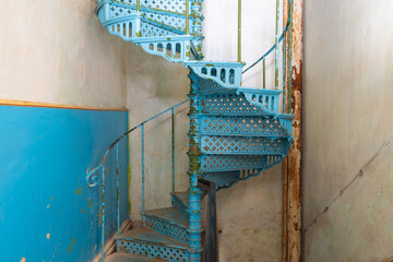 Old shabby blue metal spiral staircase in the interior of the Sharovsky castle, Ukraine