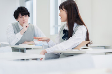 同級生と教室で仲良く話す高校生