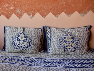 Close up of traditional colorful Moroccan seating with clay wall at a Berber home. High Atlas Mountains, Morocco.