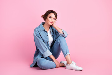 Obraz na płótnie Canvas Full length photo of adorable sweet lady dressed denim jacket sitting floor arm cheek empty space isolated pink color background