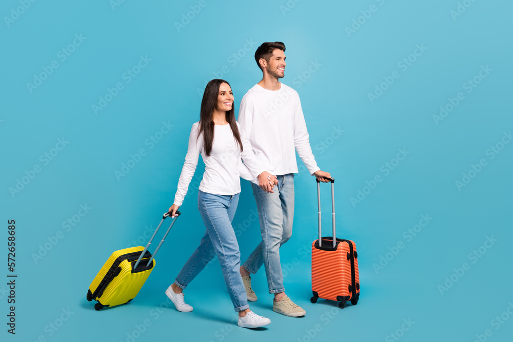 Poster full length portrait of two cheerful people hold arms walking empty space isolated on blue color bac
