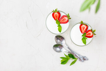 Healthy strawberry yogurt with in glasses with fresh berries over white table.