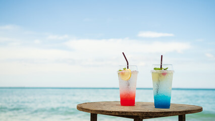 Strawberry Iceland Sodap and Blue Hawaii Italian Soda in Glass on blur Blue Sea and Sky,Tropical Summer Juice Fruit Drink,Cocktail Tourism Resort in Vacation Holidays,Snack on Food on Table at Coast.