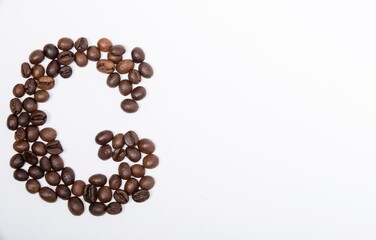 G is a capital letter of the English alphabet made up of natural roasted coffee beans that lie on a white background.
