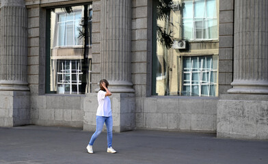 a confident young woman walks through the streets of the city, a woman smiles and enjoys life