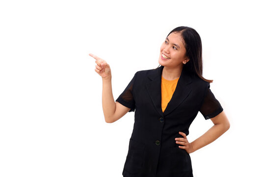 Happy young asian business woman standing while pointing at blank space beside her. Isolated