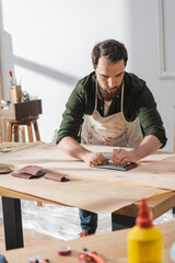 Craftsman sanding surface of wooden board in workshop.