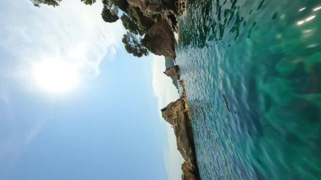 Cinematic vertical fpv shot around group of kayakers on orange kayaks floating