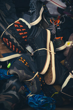 Toned photo mixed wide variety of brand-new shoes tied in rubber band in large carton box at donation center in Dallas, Texas, USA