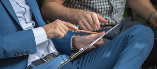 Two businessman or gay sitting at chair in park while using digital tablet and paper work plan for talk discussion team working online togetherness while consulting.