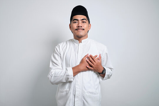 Asian Muslim Man Wearing Casual Clothes Smiling With Hands On Chest With Closed Eyes And Grateful Gesture On Face