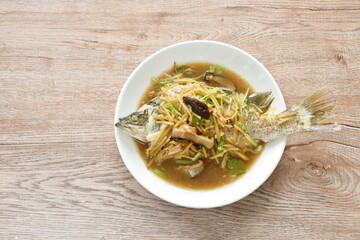 steamed bass fish dressing soybean gravy sauce topping slice ginger and mushroom on plate 