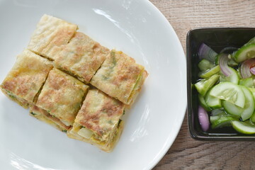 fried Murtabak roti stuffed beef meat on plate dipping sweet pickled cucumber sauce