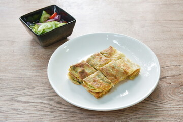 fried Murtabak roti stuffed beef meat on plate dipping sweet pickled cucumber sauce