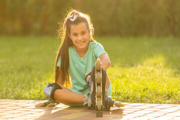 little girl wears roller skates on beautiful summer day in a park