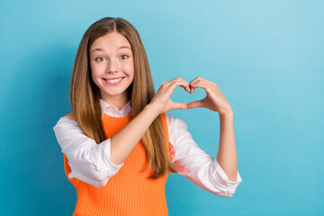 Photo of adorable postive lady wear trendy clothes demonstrates heart symbol empty space isolated on blue color background