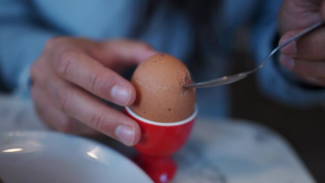 Oeuf a la coque. Hand breaking top soft egg head. Morning breakfast nutritious food rich in protein