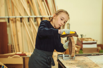 Young carpenter working with wood and sandpaper in craft workshop. School, development and learning...