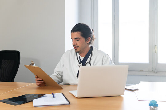 Focused doctor checking information on clipboard