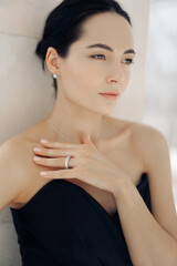 Portrait of pensive young woman with jewelry in black dress.