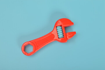 Red toy wrench or spanner isolated on a blue background.