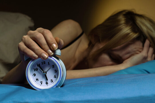 The Woman Cannot Wake Up In The Morning. Poor Sleep, Violation Of The Regimen, Lack Of Sleep Concept. A Middle-aged Woman Turns Off The Alarm Clock.