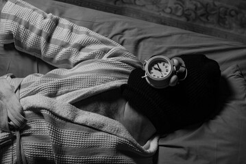 Thief of time, procrastination concept. A man in a balaclava lies and sleeps with an alarm clock on...