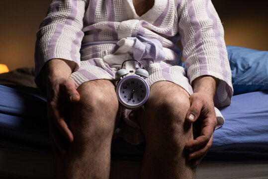 Andropause concept. Alarm clock between male legs. Male menopause, impotence, biological clock.