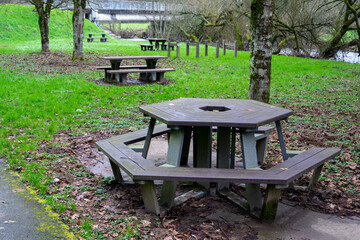 Empty benches with tables for tourists to rest on the green grass near the river. A place of rest for tourists and travelers.