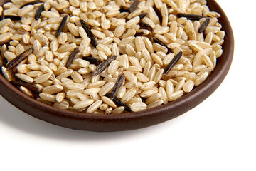 Mixture of brown and black wild rice in a clay ceramic bowl close-up isolated on a white background