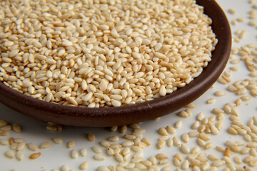 White roasted sesame in clay ceramic bowl closeup isolated on white background