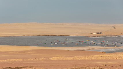 Panorama of a bay with a group of colorful fishermen's boats floating next to the Paracas desert Peru