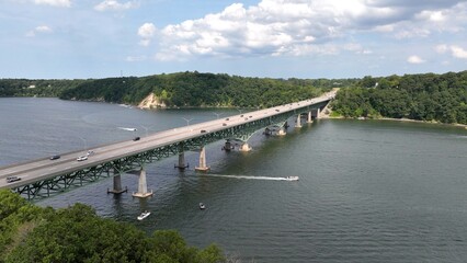 Bridge with cars traveling across Irondequoit Bay by Lake Ontario with boats on water below
