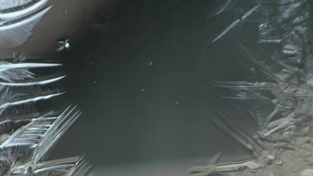 Frost draws a magical pattern on the glass. Winter background for postcards