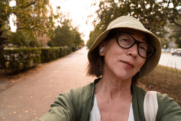 Closeup portrait of smiling senior asian woman in hat and glasses speaking during video call