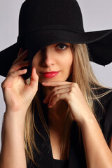Young woman with hat in studio posing on black background
