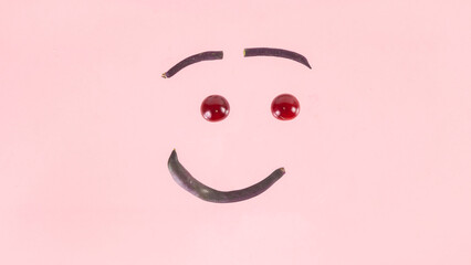 Face made from purple asparagus beans and cherries. Concept of berries season and proper nutrition.