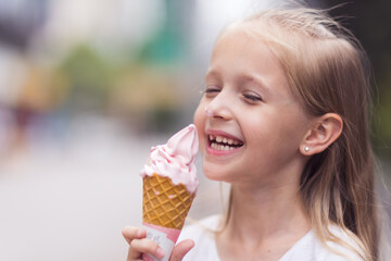 Pretty little caucasian girl with blonde hair eight years old eating licking vanilla ice cream in...