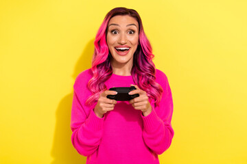 Photo of impressed cheerful girl toothy smile hands hold controller playing video games isolated on yellow color background