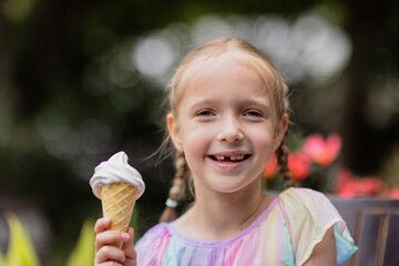 Pretty little caucasian girl with blonde hair eight years old eating licking vanilla ice cream in...