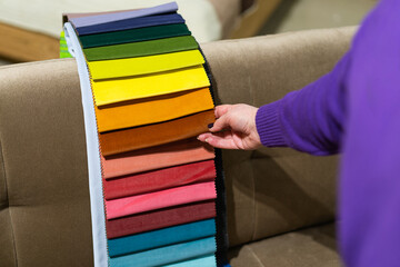 The woman chooses the fabric on the sofa. A women looks at tissue samples. Selects the color of the...