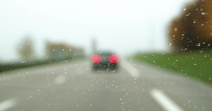 car windshield window covered with multiple tiny water rain drops driving commuting on the highway
