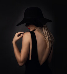 Young woman with hat in studio posing on black background