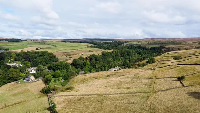 Aerial footage of the beautiful village of East Morton in Keighley in Yorkshire in the UK, showing farmers fields and trees on a bright sunny day in the summer time.