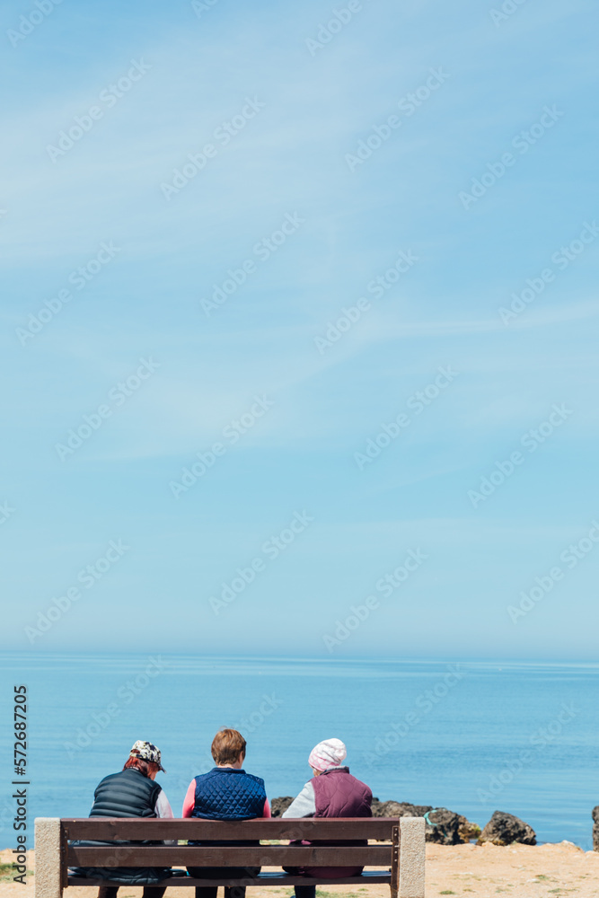 Wall mural people on a bench sit and look at the sea on the shore